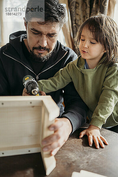 Sohn lernt  mit Vater zu Hause ein Vogelhaus zu bauen