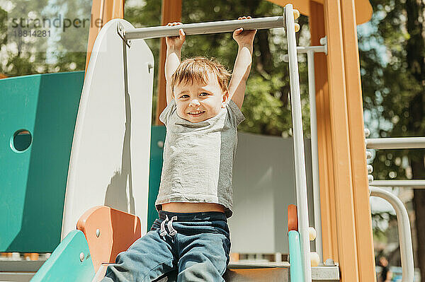 Junge hängt an Rutsche auf Spielplatz
