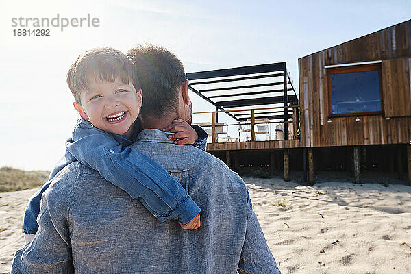 Glücklicher Sohn mit Vater am Strand an einem sonnigen Tag