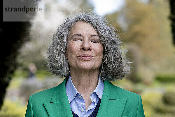 Lächelnde ältere Frau mit geschlossenen Augen  die die Natur genießt