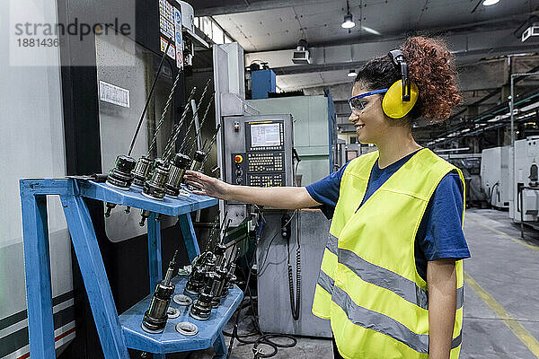 Wartungsingenieur in Arbeitsschutzkleidung überprüft Maschinenteile in einer modernen Fabrik