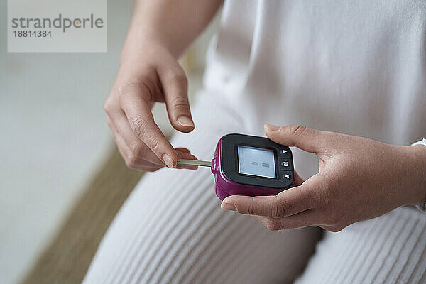Frau hält digitales Glukometer zu Hause