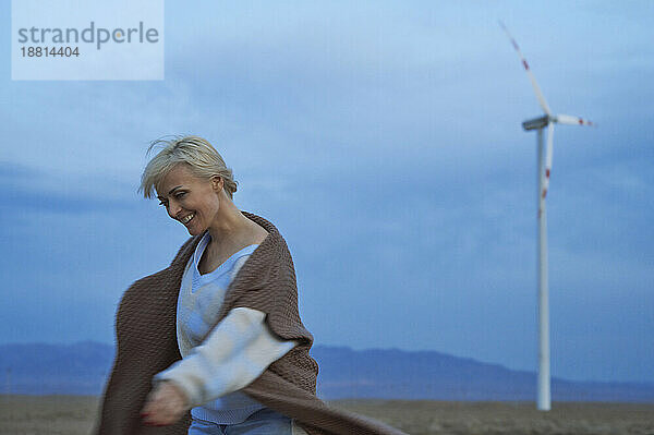 Lächelnde Frau  die Spaß in der Nähe von Windkraftanlagen in der Wüste hat
