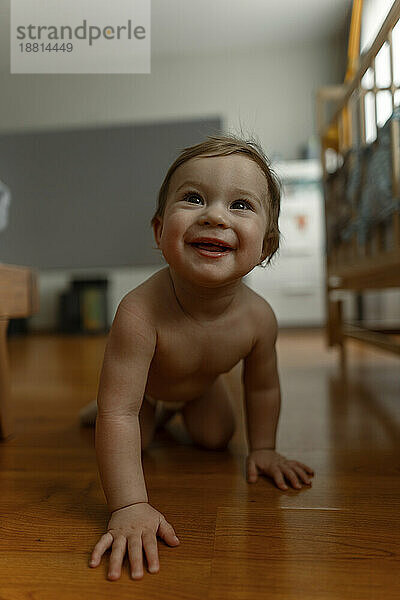 Smiling baby girl crawling in bedroom