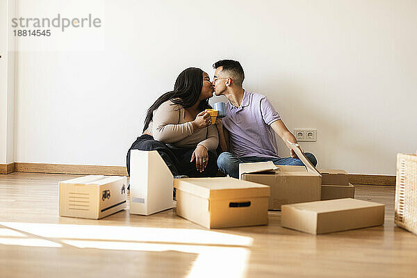 Couple kissing sitting by cardboard boxes in new home
