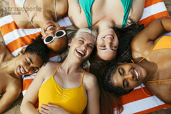 Gemischtrassige Freunde liegen auf einem Strandtuch