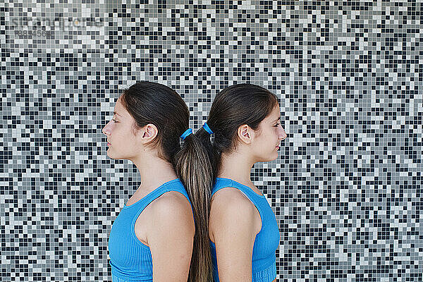 Sisters standing together in front of textured wall