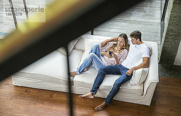 Junger Mann und Frau benutzen zu Hause Smartphone