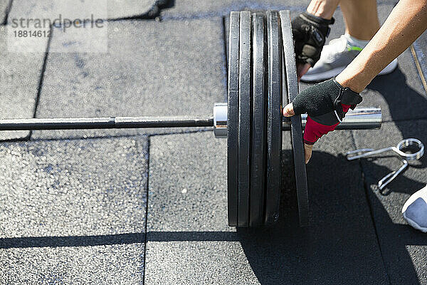 Frau bereitet Hantelgewichte im Fitnessstudio auf dem Dach vor