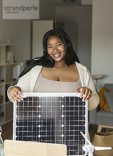 Lächelnde Geschäftsfrau mit Solarpanel im Heimbüro