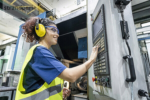 Wartungstechniker in Schutzkleidung bedient CNC-Maschine in der Fabrik