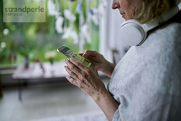Ältere Frau schreibt Textnachrichten und nutzt das Smartphone zu Hause