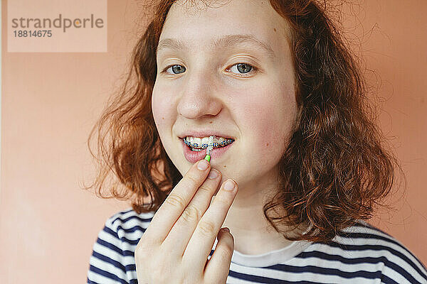 Mädchen reinigt Zahnspangen mit Interdentalbürste