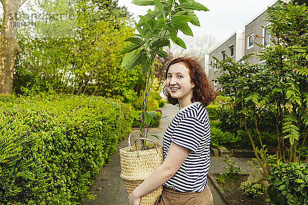 Lächelndes Mädchen  das mit Avocadopflanze steht