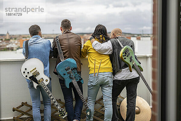 Rockmusiker stehen zusammen mit E-Gitarren auf dem Dach