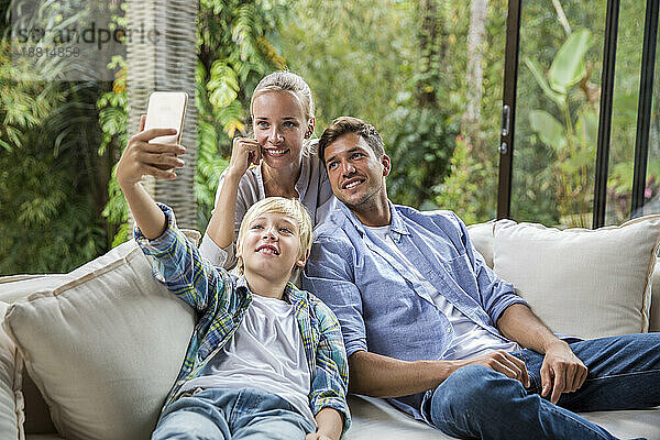 Glücklicher Mann und Frau mit Junge machen Selfie per Smartphone