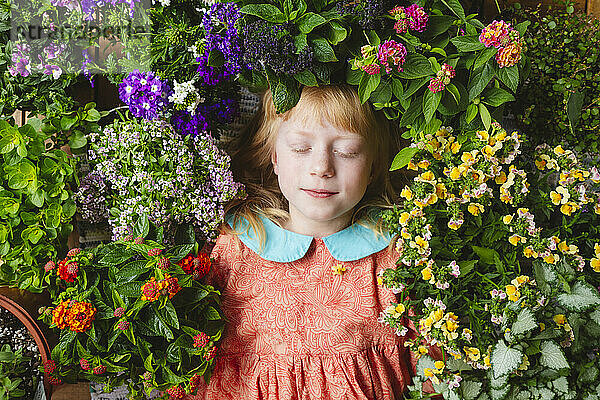 Mädchen mit geschlossenen Augen liegt inmitten von Blumen