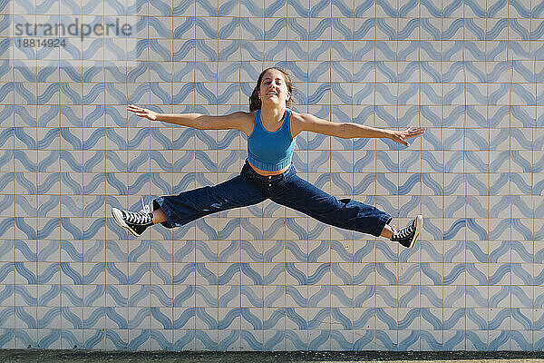 Girl jumping in front of wall