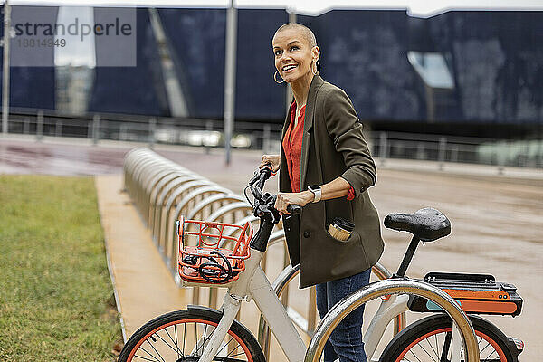 Frau hält Fahrrad am Parkplatz