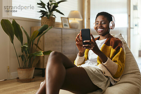 Happy woman wearing wireless headphones using smart phone