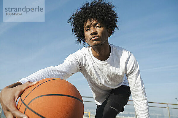 Selbstbewusster Athlet mit lockigem Haar  der Basketball spielt