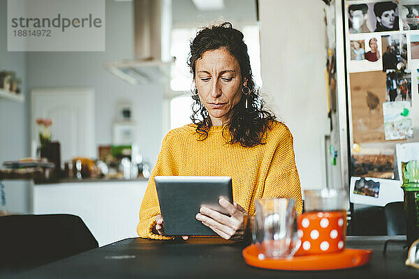 Frau sitzt mit Tablet-PC am Tisch zu Hause