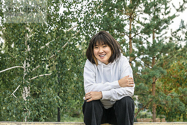 Lächelndes Mädchen sitzt auf einer Bank im Park