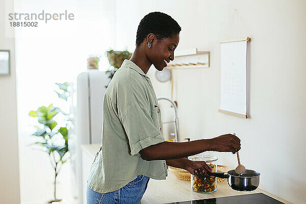 Happy young woman cooking food at home