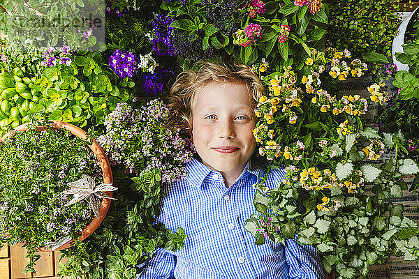 Lächelnder Junge  der sich inmitten bunter Pflanzen hinlegt