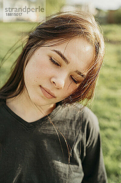 Teenager-Mädchen mit geschlossenen Augen an einem sonnigen Tag