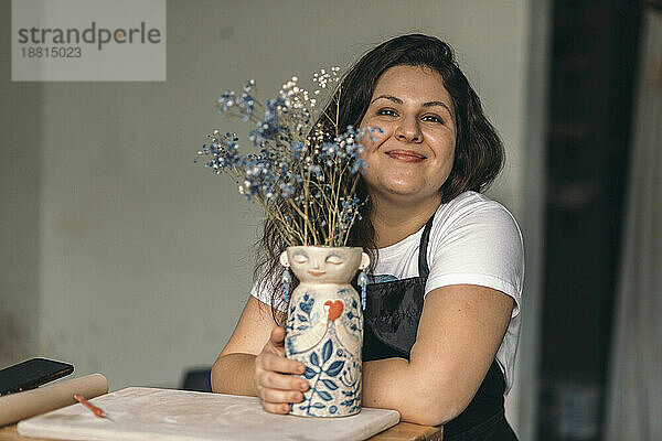 Lächelnder Töpfer mit Keramikblumenvase in der Werkstatt