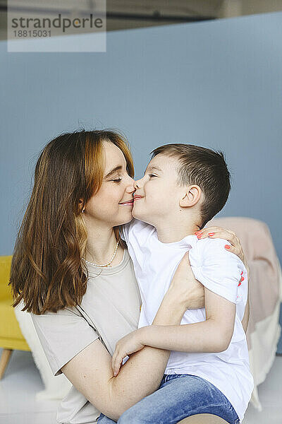 Mother kissing son in front of backdrop