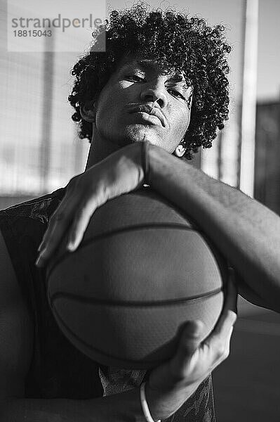 Selbstbewusster junger Sportler  der Basketball in den Händen hält
