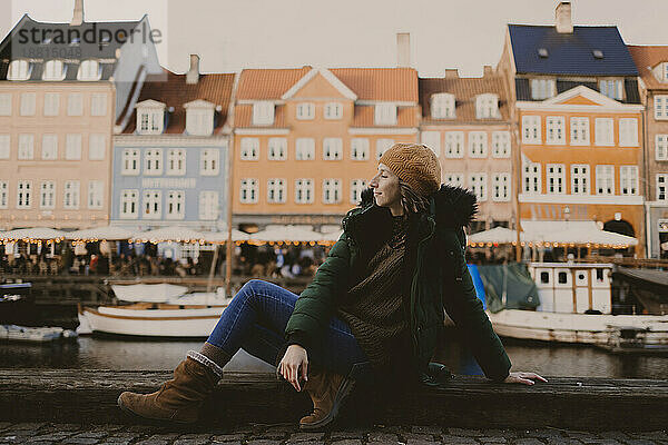 Frau sitzt am Hafen vor Gebäuden in der Stadt