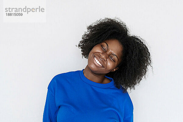 Smiling Afro woman with head cocked against white background