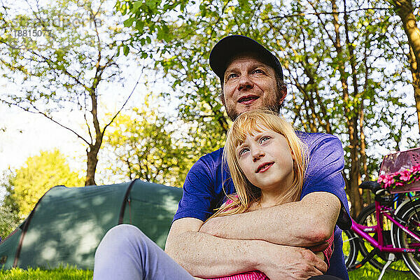 Glücklicher Vater umarmt Tochter  die im Zelt sitzt