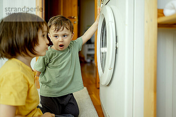 Junge mit Bruder benutzt Waschmaschine zu Hause