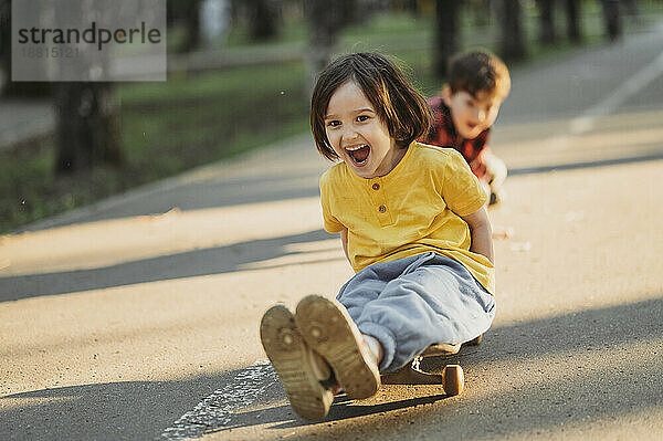 Happy siblings skateboarding on street