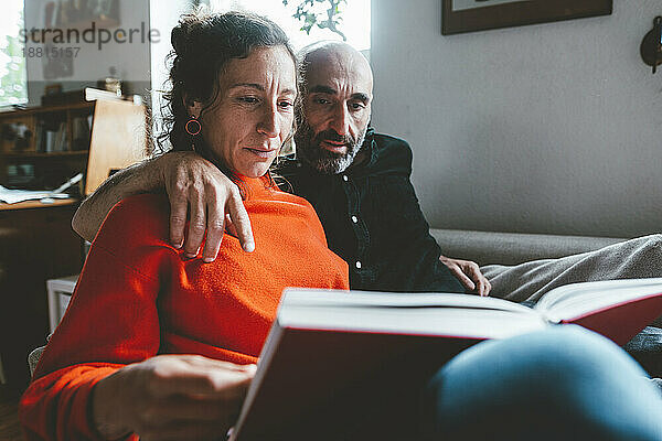 Mann und Frau lesen zu Hause gemeinsam ein Buch