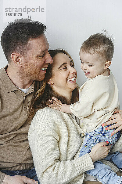 Happy family holding son against white background