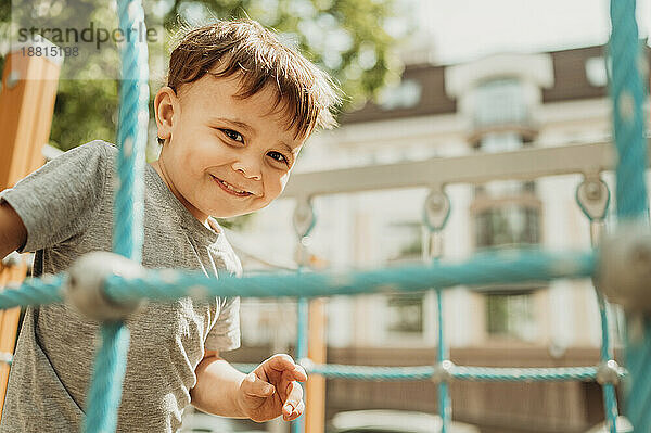 Fröhlicher Junge  der sich an einem sonnigen Tag auf dem Spielplatz vergnügt