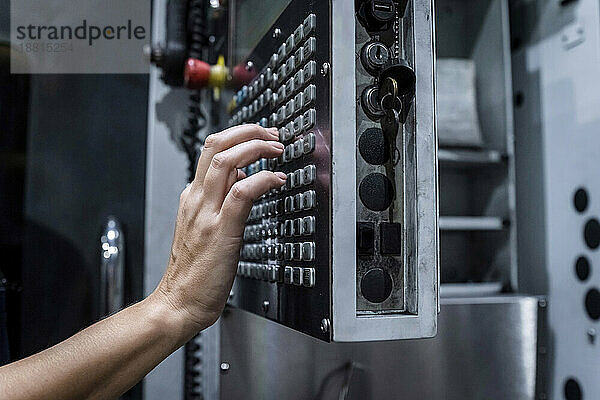 Hand eines Wartungsingenieurs  der eine CNC-Maschine in einer modernen Fabrik bedient