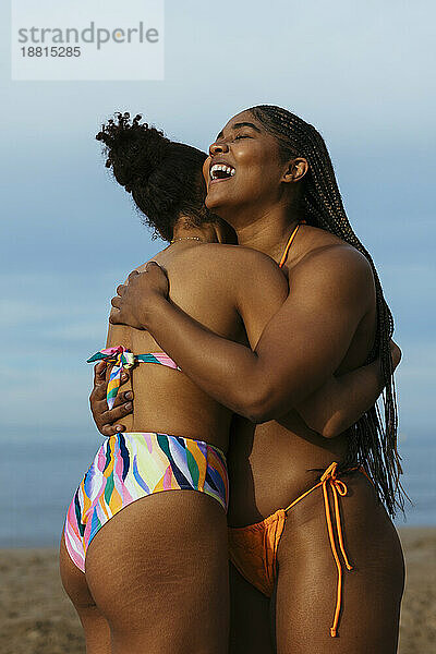 Glückliche Frau umarmt Freundin am Strand