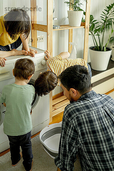 Kinder helfen Vater beim Wäschewaschen zu Hause