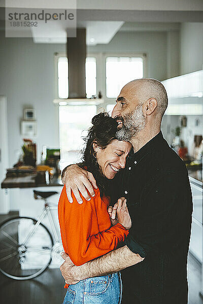 Smiling man embracing woman standing at home