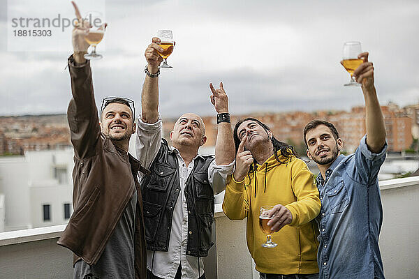Fröhliche Freunde gestikulieren und genießen gemeinsam Bier auf dem Dach