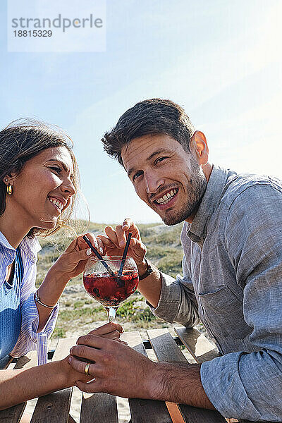 Glückliche Frau und Mann sitzen mit einem Glas Saft am Tisch