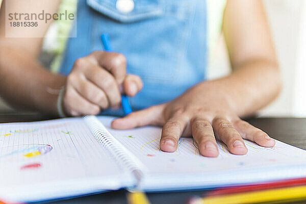 Mädchen zeichnet mit Buntstift Hand auf Notizbuch