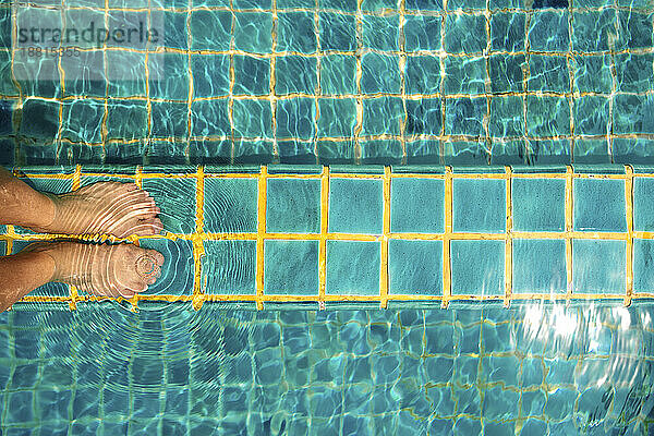 Beine einer Frau auf Fliesenboden im Schwimmbad