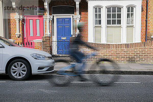 Blurred motion of delivery person riding bicycle on road